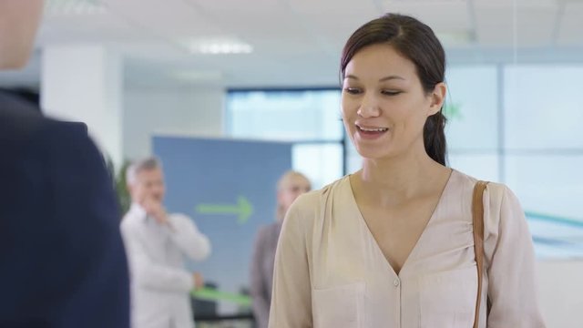  Friendly bank worker at service desk assisting queue of customers