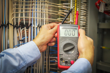 An electrician with multimeter close-up. Hands of service engineer with measuring instrument macro.