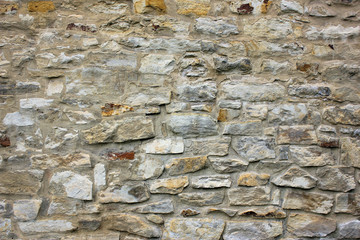 Old beige stone wall background texture close up.