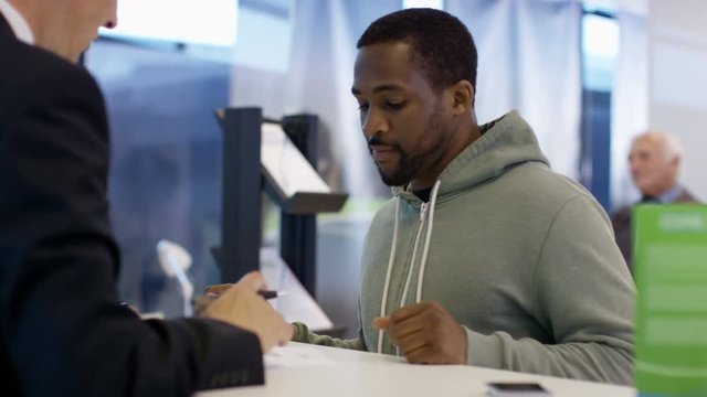  Modern city bank, worker assisting customer & getting signature on document