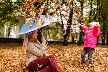 A little girl playing with autumn leaves in a city park