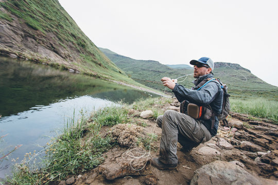 fly fisherman casting into a mountain river