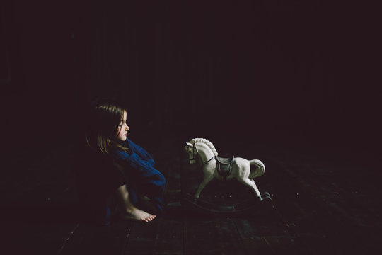 Child sitting next to toy hourse