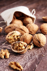 Walnut kernels and whole walnuts on rustic old wooden table.