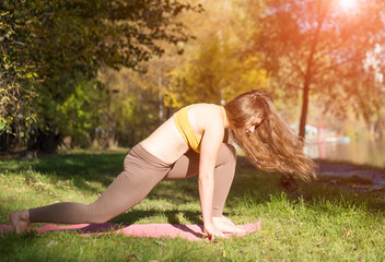 Fototapeta premium Portrait of young woman in autumn city park. Sport girl doing yoga outside