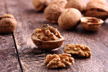 Walnut kernels and whole walnuts on rustic old wooden table.