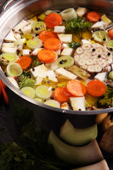 Broth with carrots, onions various fresh vegetables in a pot - c