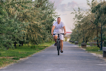 A fat man rides a bicycle along the mall during the day