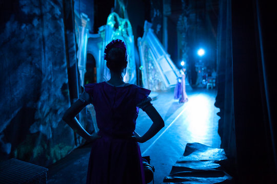 ballet, dancing, magic concept. in ghostly blue light tender silhouette of slender ballerina wearing pink dress with short sleeves waiting for her turn backstage