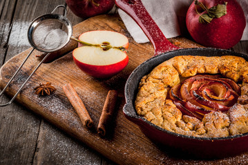 Traditional autumn baking, recipes for thanksgiving, Homemade wholegrain apple galette pie with organic apples and cinnamon, In iron cast pan, old wooden table, copy space