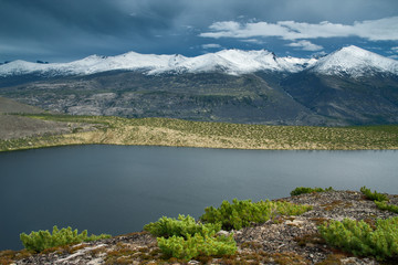 Mountain lake and mountain range with snowy peaks. Ridge Chersky, Yakutia, Russia.