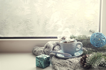 the window with a cup of hot drink