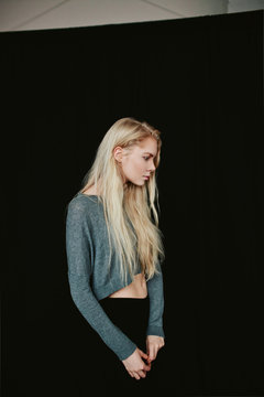 Portrait of a young blonde girl on a black background in the studio