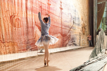 choreography, photography, dancing concept. prima ballerina in elegant blue tutu and warm sport sweatshot practicing fouette in the wings for photographer © melnikofd