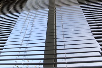 Fototapeta na wymiar White horizontal aluminium blinds on the windows.