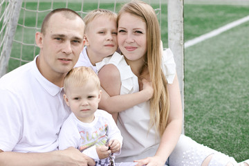 A family of four on a football field. Bright sunny summer day.