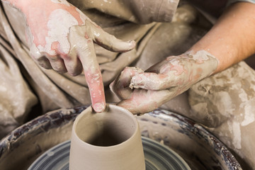 pottery, workshop, ceramics art concept - closeup on man's hands work with potter wheel and raw...