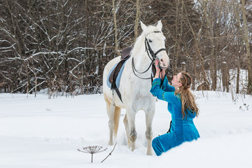 Fototapeta na wymiar Woman in national dress and white horse in a winter forest