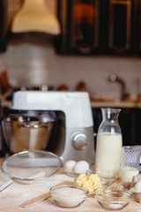 Baking ingredients on kitchen table. White products prepare for cooking on wooden cutting board. Lifestile food concept.