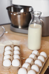 Home cooking still life of eggs in box and milk in glass bottle.