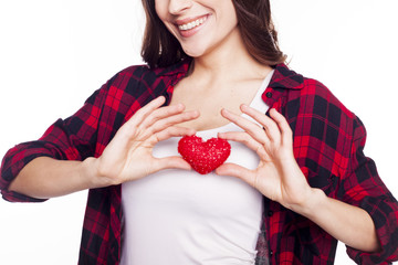 Young brunette girl holds a toy heart on a white background