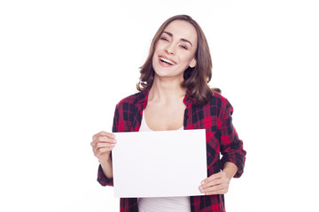 Naklejka premium Young beautiful girl smiles and holds in her hands a white paper for an inscription on a white background isolated