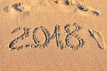 2018 inscription on the sand and footprints around. New Year card background toning. The concept of the coming Christmas.
