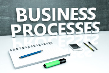 Business Processes - text concept with chalkboard, notebook, pens and mobile phone. 3D render illustration.