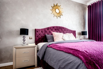 Interior of purple beautiful, cozy and stylish bedroom, with drapes and nightstands