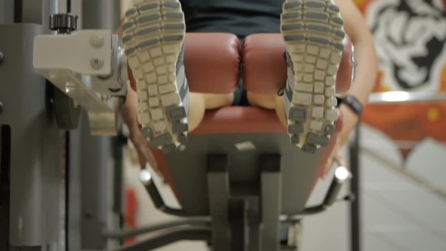 Man is doing leg extension exercise in gym