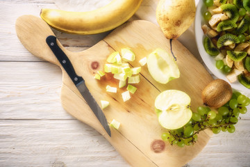 Ingredients for fruit salad. Cutting apple