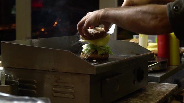 The chef puts the cheese and stove, on top of burge and heats it in the stove.