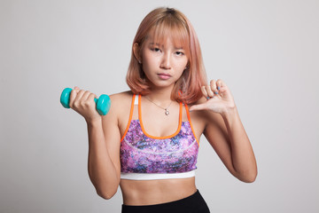 Naklejka premium Beautiful Asian healthy girl thumbs down with dumbbell.