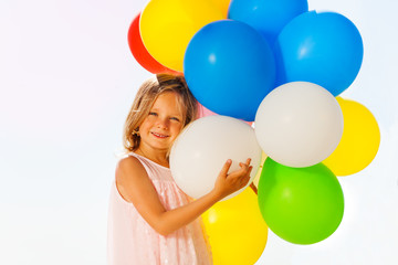 Happy little girl playing with colorful balloons