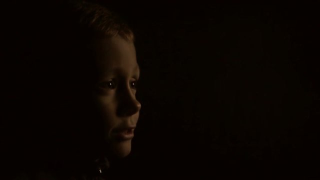 A child in the dark is watching TV