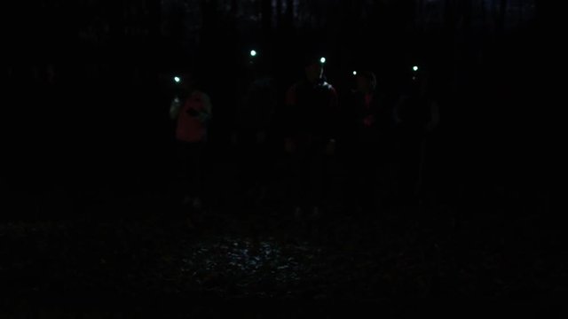 Group running in the woods at night wearing lamps on headgear.