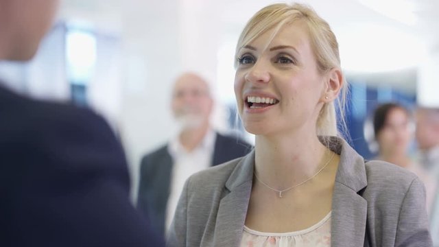  Friendly bank worker assisting queue of customers with enquiries