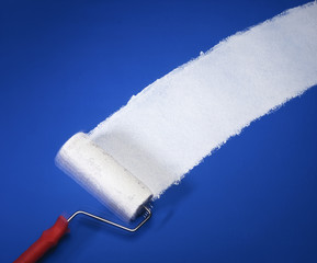 Obraz premium Paint roller applying white paint on blue wall background