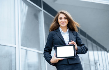 Successful businesswoman or entrepreneur using a digital tablet computer and talking on cellphone standing in front of his office.