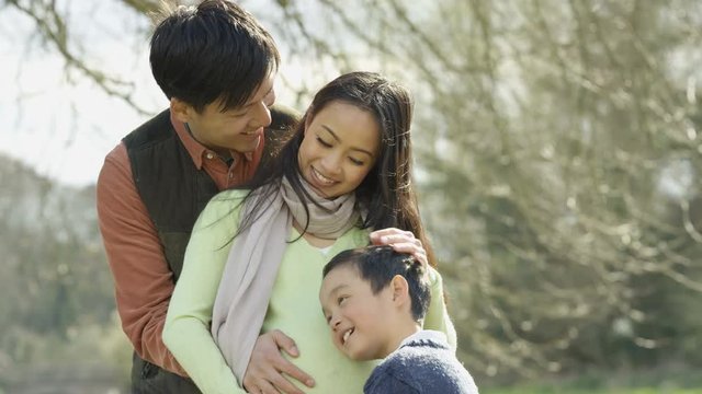  Happy family relaxing in the park parents expecting baby with cute little boy
