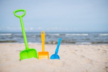 Three colorful toy shovels on the beach