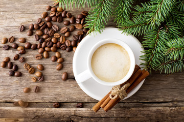 A cup of coffee with the branches of the Christmas tree on a wooden table