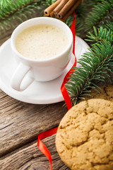 A cup of coffee with the branches of the Christmas tree on a wooden table