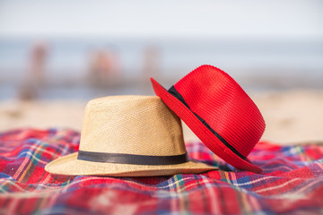 Red and white straw hats on the colorful blanket on the . beach