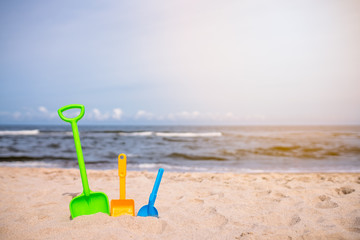 Three colorful toy shovels on the beach