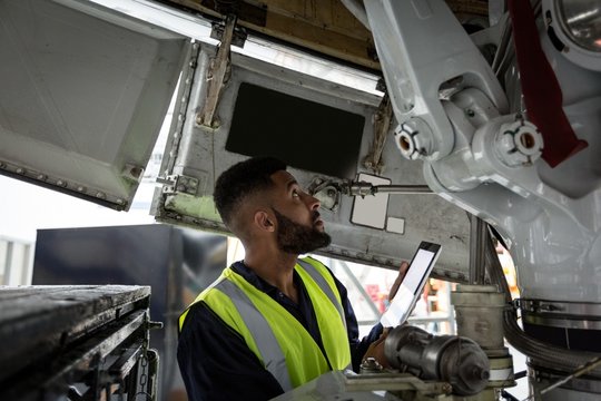 Male aircraft maintenance engineer examining engine of an
