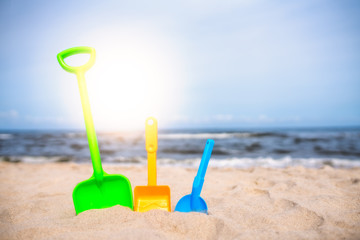 Fototapeta na wymiar Three colorful toy shovels on the beach