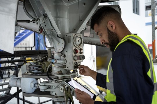 Male aircraft maintenance engineer examining engine of an