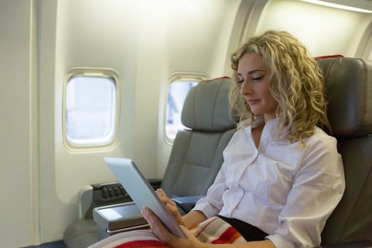 Woman using digital tablet while sitting in an aircraft seat