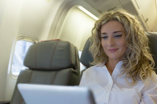 Woman using digital tablet while travelling in an aircraft seat